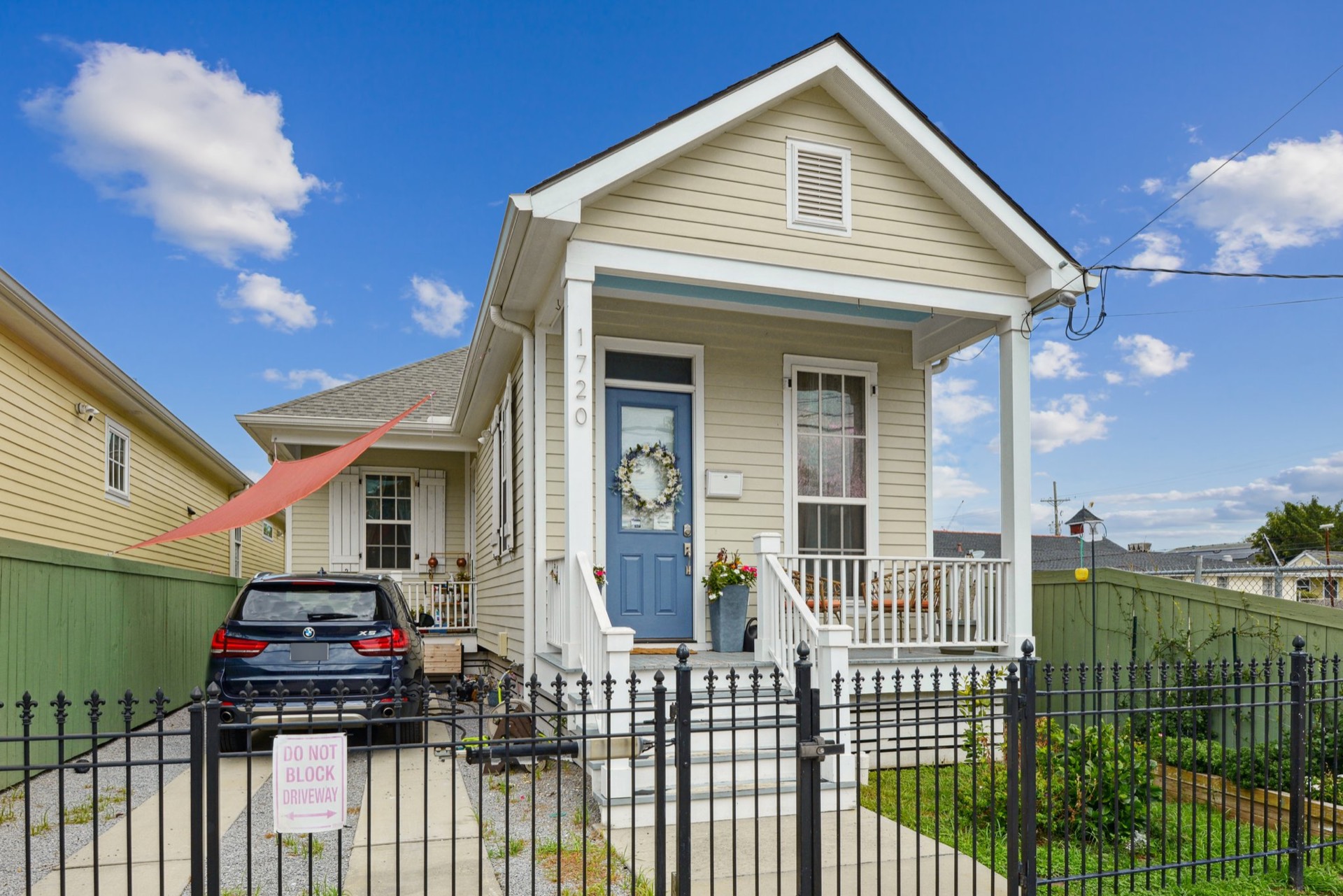 Classic New Orleans shotgun-style home with front porch and blue door