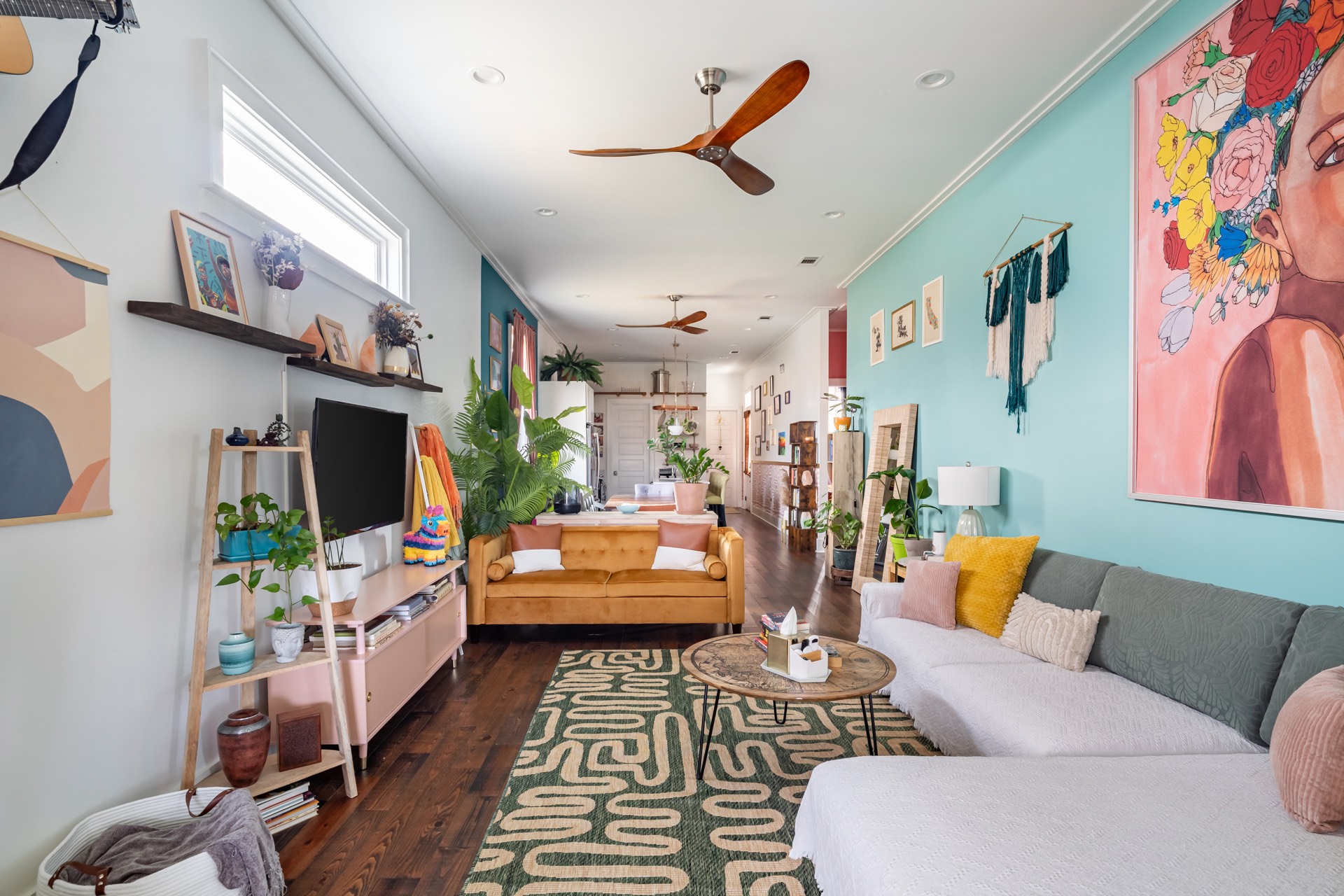 Colorful living room with teal walls, eclectic art, and natural light