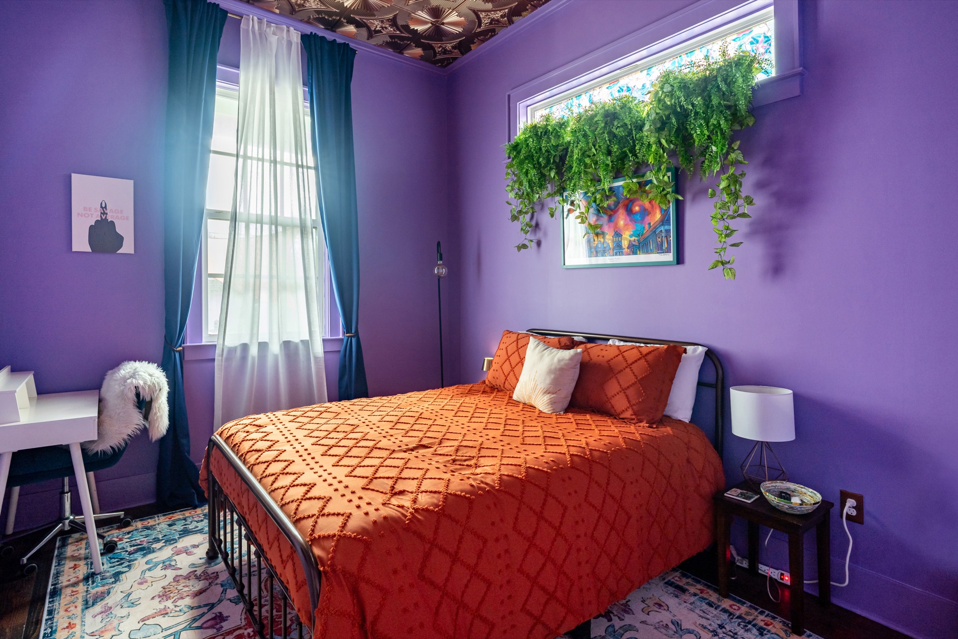 Purple bedroom with wallpaper ceiling and orange bedding